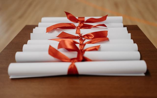 Zwinięte dyplomy przewiązane czerwoną wstążką